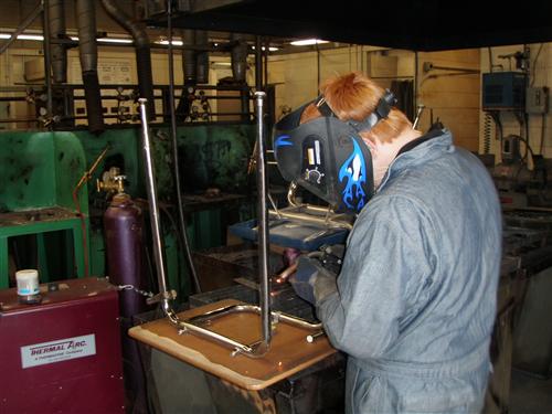 Students welding wearing gray overalls