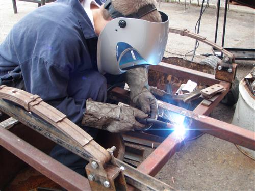 Single student welding wearing a protective shield.