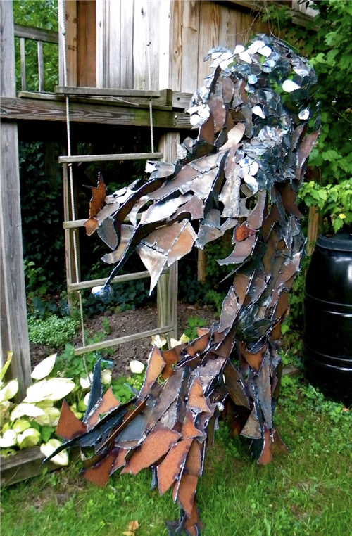 A piece of steel art with many varying shapes and sizes. About 6 feet tall.