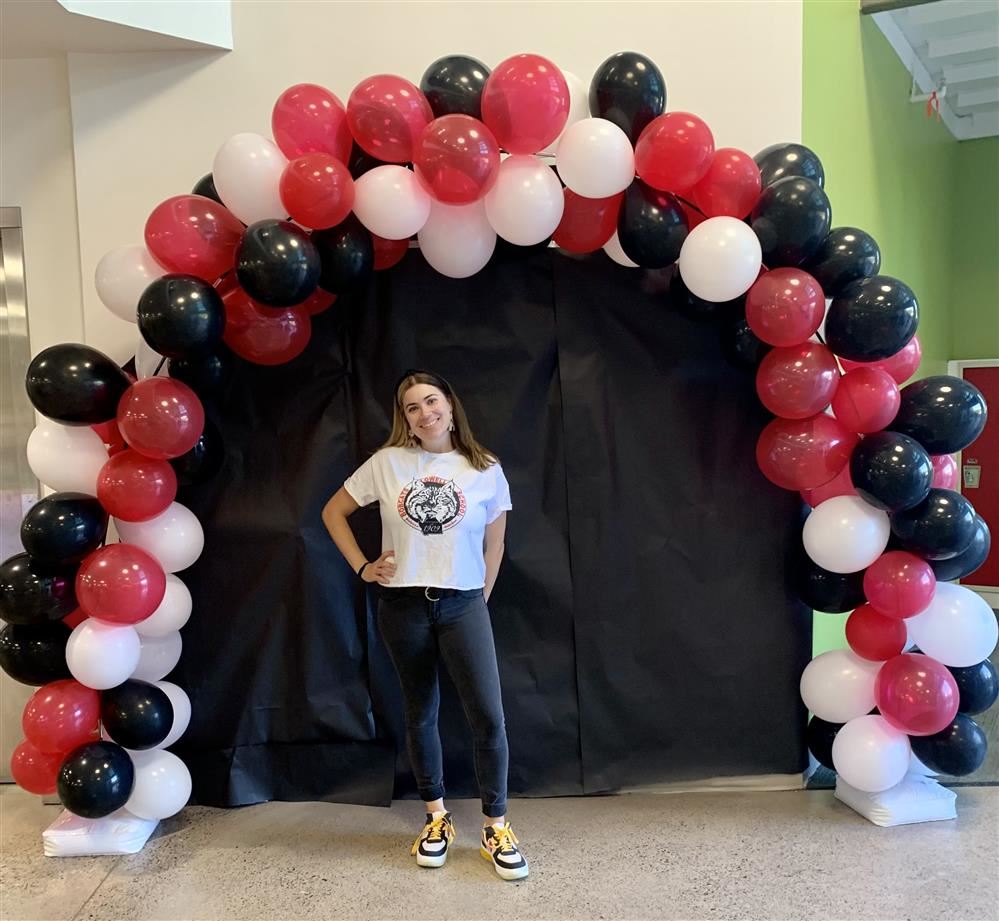 Ms. Hewey posing in front of a balloon arch